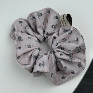 Détail d'un chouchou floral en tissu rose vintage avec une étiquette de marque élégante