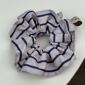 Détail d'un chouchou en tissu gris clair à rayures bleues et étiquette Forever