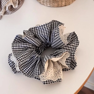 Détail d'un chouchou à carreaux noirs et blancs avec bordure en dentelle fleurie
