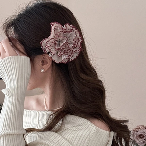 Elegante pinza per capelli a fiore con petali color crema e bordi rossi su modella