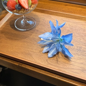 Detailed macro view of a vibrant blue silk lily flower hair clip on a rustic wooden tray