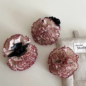 Dettaglio del fermaglio floreale con tessuto increspato bianco e bordo rosso