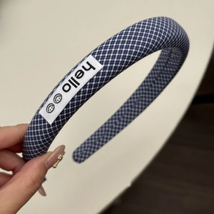 Gros plan sur un serre-tête en vichy bleu rembourré avec étiquette tissée hello smiley