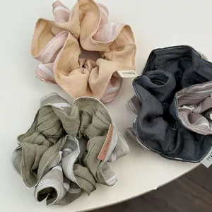 Three-piece set of large ruffled scrunchies in pink, green, and charcoal textured fabric