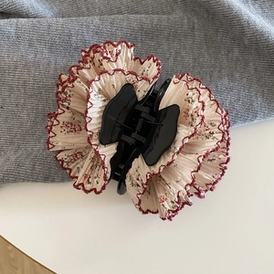 Dettaglio molletta per capelli a fiori con tessuto plissettato e bordi smerlati