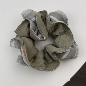 Olive green and striped pleated fabric scrunchie with a brown decorative tag detail