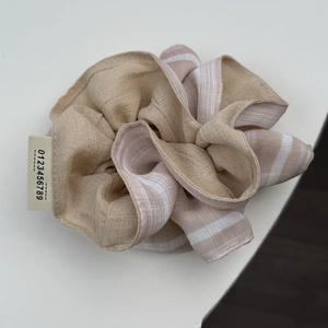 Detail view of large striped fabric scrunchie with pleated texture and numbered label
