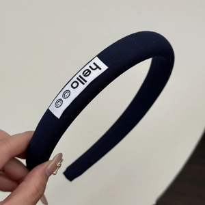 Détail rapproché d'un serre-tête éponge bleu marine avec écusson brodé hello smile