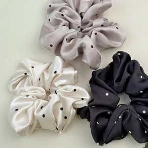 Lot de trois chouchous en satin à pois coloris crème, gris clair et noir