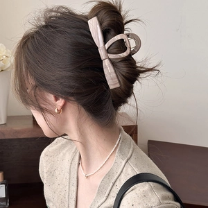 Detail of a large marble texture bow hair claw clip styled on woman's hair
