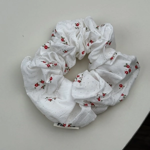 Gros plan d'un chouchou blanc avec fleurs rouges et motif à pois noirs tissu