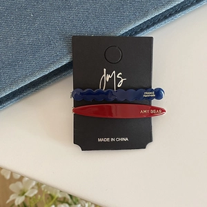 Minimalist colorful acetate hair clips in wavy blue and oval red on black card display