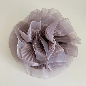 Détail du chouchou en organza mauve avec des plis superposés et un design de fleur froncée