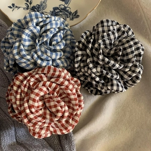 Plaid fabric flower hair clips in blue, red and black colors on soft knit background