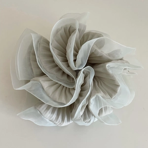 Détail du tissu plissé gris et bordure en organza blanc sur le grand chouchou
