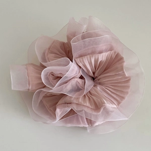Détail d'un chouchou en organza rose pâle avec couches plissées et texture florale