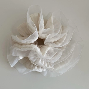 Détails des plis en organza superposés sur le chouchou ivoire au style élégant