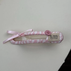 Détail de la pince à cheveux à rayures roses avec un nœud et un bouton en résine