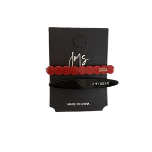 Chic acetate hair clip set with red wavy and black oval designs on display card