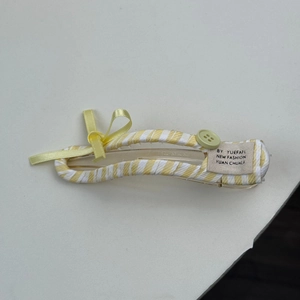 Détail de la pince à cheveux à rayures jaunes avec nœud et décoration de bouton vert menthe