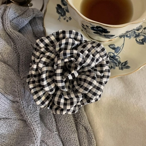 Close-up of black and white checkered fabric flower hair clip with rose petal texture