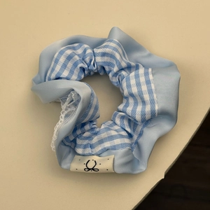 Détail du chouchou en satin à carreaux bleus avec dentelle et étiquette de marque