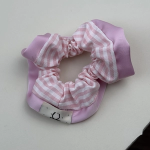 Détail du chouchou à rayures roses et blanches avec texture satinée et étiquette sourire