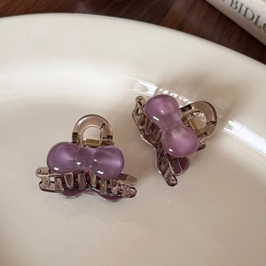 Gros plan de mini pinces à cheveux à nœud violet et marron sur une assiette en céramique