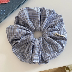 Detail of blue and white plaid scrunchie with cotton fabric texture and small woven label