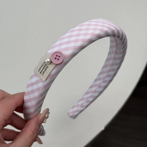 Détail d'un bandeau à rayures roses avec perles élégantes et ornements de boutons