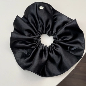 Detail of black satin hair scrunchie with silk ribbon bows and silver Lucky metal tag