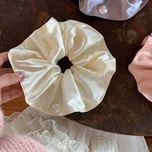Close-up of elegant satin scrunchies with white pearls on a vintage wooden surface
