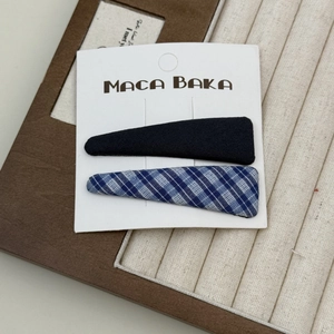 Detail eines Sets aus blau karierten und schwarzen Stoff-Haarspangen auf einem Schmucktablett