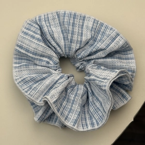 Detail of blue plaid scrunchie with white lace trim and breathable fabric texture