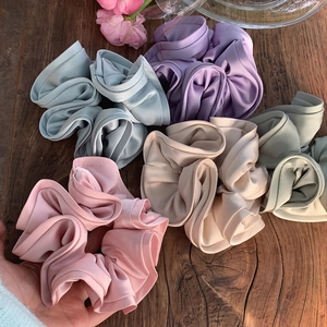 Chouchous élégants en satin aux couleurs pastel sur un fond de bois rustique