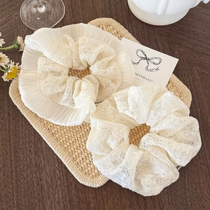Elegantes Set aus zwei weißen Spitzen-Haargummis auf einem rustikalen Holztisch