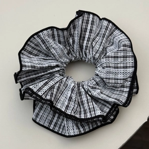 Close-up of black and white checkered scrunchie with lace trim and soft pleats
