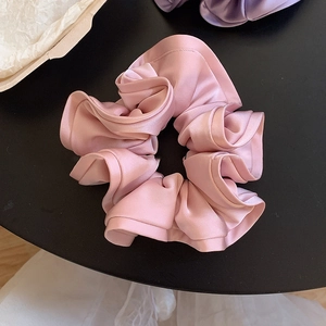 Gros plan d'un chouchou en satin rose avec texture en soie et plis élégants sur table