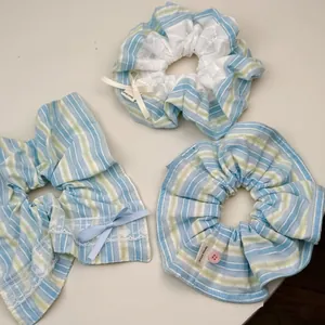 Close-up of handmade blue and yellow striped hair scrunchies with lace and ribbon details
