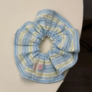 Detail of blue striped fabric scrunchie with pink button and Hand Made label