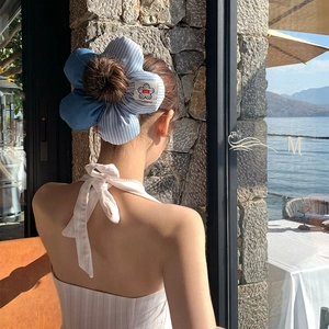 Large striped floral scrunchie in blue fabric shown on model with seaside vacation background
