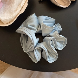 Vue détaillée du chouchou en satin bleu clair avec texture soyeuse et design plissé élégant
