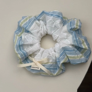 Detailed close-up of handmade blue striped scrunchie with lace and bow details