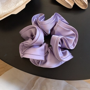 Gros plan sur le chouchou en satin violet aux plis élégants et texture soyeuse