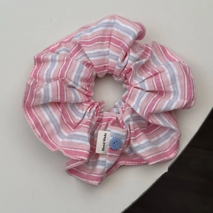 Detail of pink and blue striped scrunchie with handmade label and blue button accent