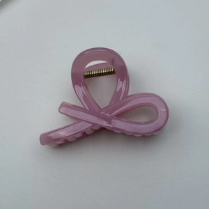 Detail of jelly pink translucent ribbon hair claw with visible gold spring mechanism
