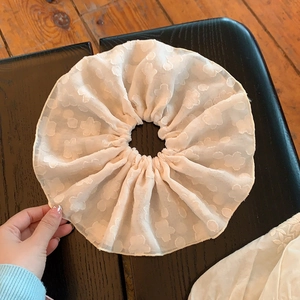 Détail d'un chouchou géant en mousseline rose pâle avec texture jacquard à motifs floraux
