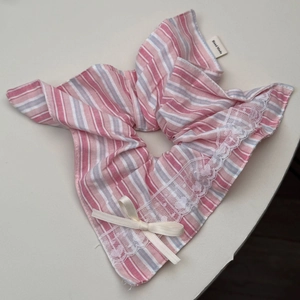 Close-up of pink striped fabric hair tie with lace trim and handmade ribbon bow detail