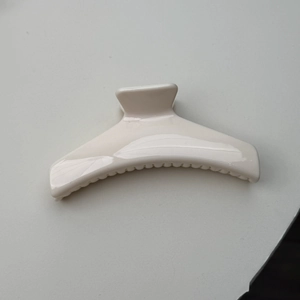 Top view of a minimalist creamy white glossy hair claw clip for elegant bun hairstyles