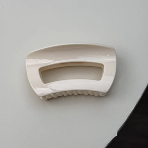 Detail of minimalist creamy white hair claw clip with a glossy porcelain-like finish